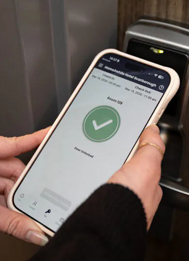 A person holding a mobile phone unlocking a door.