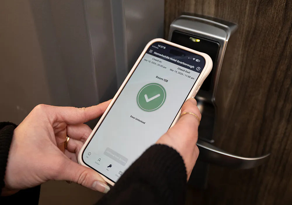 A person holding a mobile phone unlocking a door.